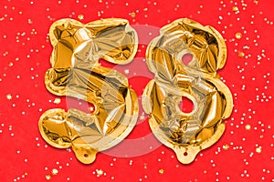 The number of the balloon made of golden foil, the number fifty-eight on a red background with sequins.