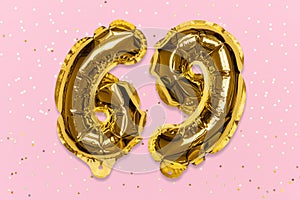 The number of the balloon made of golden foil, the number sixty-nine on a pink background with sequins.