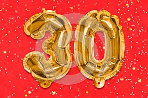 The number of the balloon made of golden foil, the number thirty on a red background with sequins.