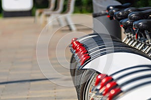 A number of bikes for rent rear wheels with red cataphotes.