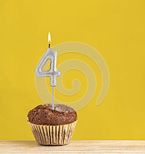 Number 4 birthday candle - Chocolate cupcake on a yellow background