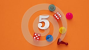 Number five in white with pieces and gambling dice - Orange eva rubber background