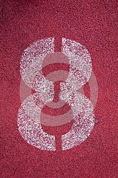 Number eight on running track. White track number on red rubber racetrack