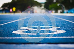 Number eight on the start of a running track .Blue treadmill with different numbers and white lines.Selective focus on Number.