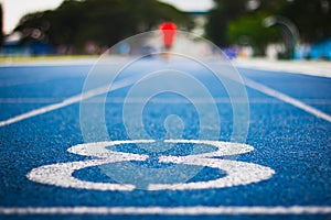 Number eight on the start of a running track .Blue treadmill with different numbers and white lines.Selective focus on Number.