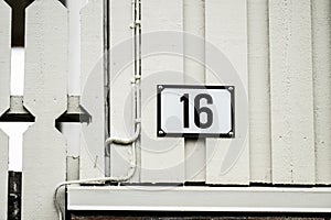 Number 16 on the facade of a baige house..