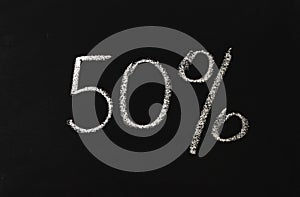 Number fifty percent written in white chalk on a black chalkboard. 50 photo