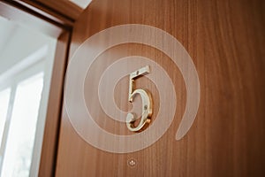 number five sitting on the side of a wooden door in front of a window
