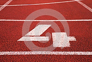 Number four. White track number on red rubber racetrack, texture of racetracks in stadium