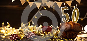 Number 50 golden festive burning candles in a cake, wooden holiday background. fifty years of birth. the concept of