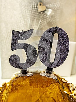 Number 50 happy birthday celebration candle. Candles on a homemade cake. Silver background