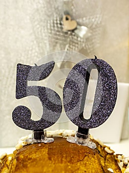 Number 50 happy birthday celebration candle. Candles on a homemade cake. Silver background