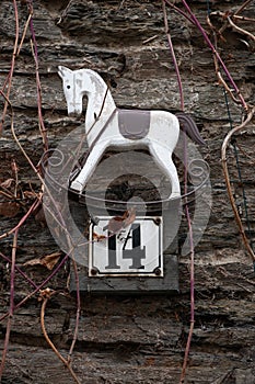 Number 14 house number sign with small rocking horse decoration on stone wall photo