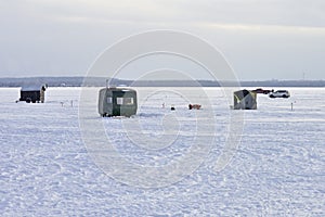 A number of ice fishing shacks or shanties litter the river view on a traditional Winter in Canada.  Canadians love ice fishing photo
