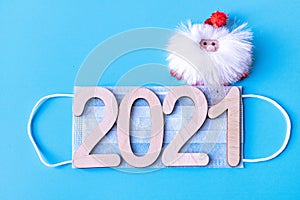 Number 2021 on a medical protective mask and Santa Claus on a blue background. Christmas and New Year concept in coronavirus