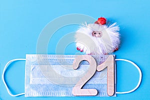 Number 21 on a medical protective mask and Santa Claus on a blue background. Christmas and New Year concept in coronavirus