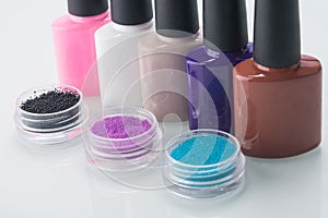 A number of multi-colored varnishes and broths in containers for nail decoration, on a white background, close-up