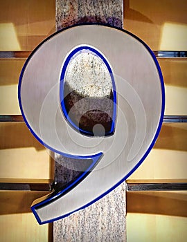 Number Nine Signage in scratched metal mounted on a wooden wall. photo