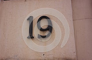 Number nineteen is made of metal, fastened with metal screws on the wall