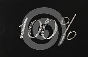 Number one hundred percent written in white chalk on a black board. 100