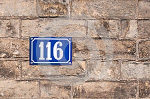 Number one hundred and sixteen painted on metal plate on brick w