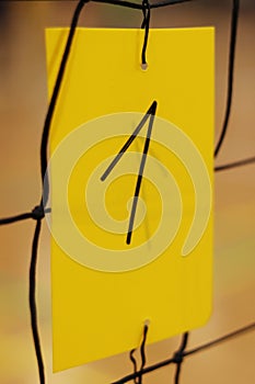 Number One written by black marker on yellow plastic card holds on volleyball net. Number used to identify courts in sports hall