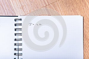The number pi is written in a notebook with a pen. Pi day number concept