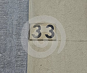 Number plate. Number thirty-three against wall background