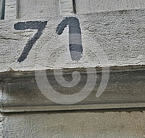 Number seventy-one (71). An inscription painted in black paint on an uneven stone surface.
