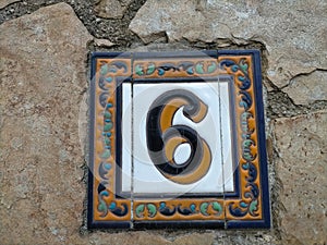 Number six (6) on a ceramic tile decorated with friezes