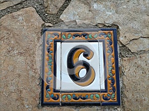 Number six (6) on a ceramic tile decorated with friezes