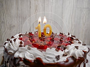 Number ten candle lit on top of a chocolate cherry cake