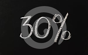 The number thirty percent written in white chalk on a black chalkboard. 30