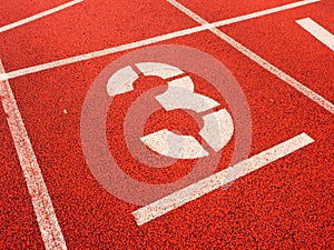 Number three. White track number on red rubber racetrack,