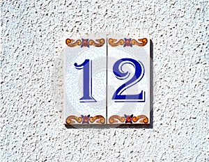 Number twelve, 12, on a decorative tile.