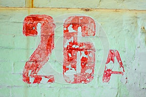 Number Twenty Six Drawn By Red paint On Whitewashed Brick Wall. Shabby Building Facade With Damaged ÃÂ¡rack Plaster photo