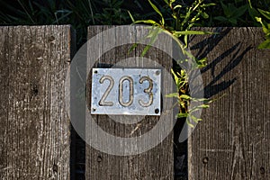 Number two hundred and three on a metal plate nailed to old boards