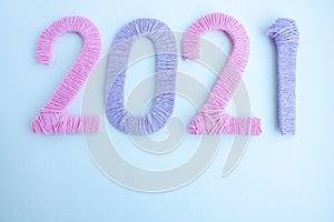 The numbers 2021 are made of pink and lilac threads on a white background. The concept of a New year