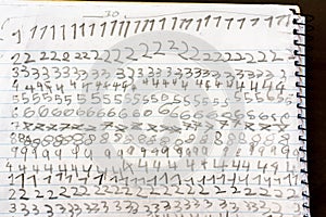 Numbers written by a child repeated on the sheet of paper notebook at school