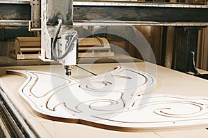 Numerically controlled woodworking machine cuts rounded complex lines on the canvas. Computer numerical control. CNC.