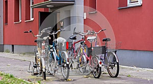 Numerous bicycles in various conditions parked in front of an apartment building.