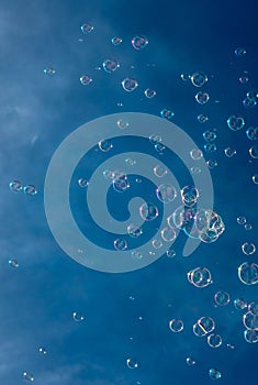 Numerous Colorful Soap Bubbles Float In Mid-Air In Front Of Blue Sky