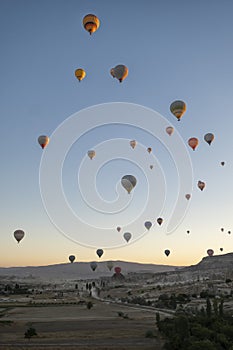 numerous hot air balloons flying over the fairy chimneys, at the Goreme airfield at dawn, Cappadocia, Turkey