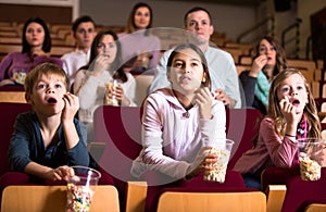 Numerous spectators eating popcorn and watching a movie