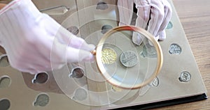 Numismatist examining old coin with magnifying glass closeup 4k movie slow motion