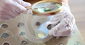 Numismatist in white gloves looking at old coin through magnifying glass closeup 4k movie slow motion