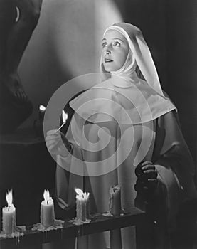 Nun lights candles in church photo