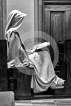 Nun sitting, reading Bible and praying in the church