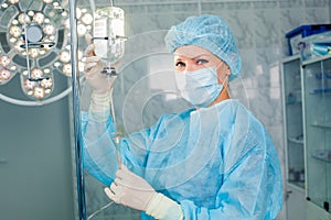 Nurse adjusting infusion bottle with against photo