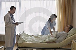 Nurse Adjusting Patient In Bed At Hospital photo